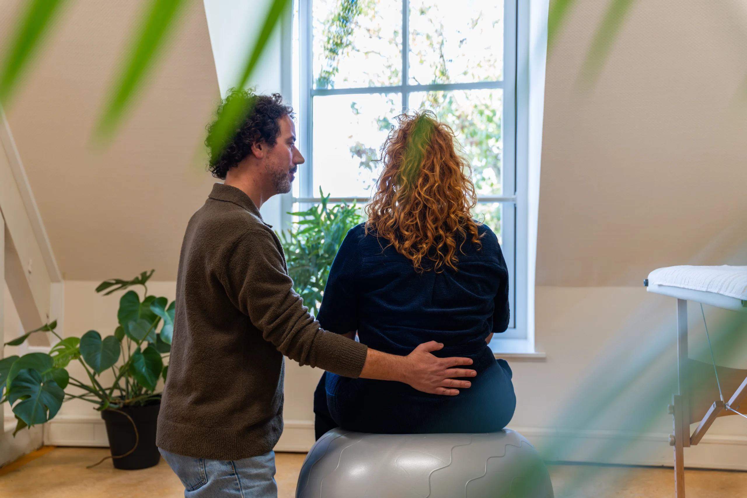Haptotherapeut ondersteunt cliënt met hand op de onderrug tijdens een haptotherapie oefening