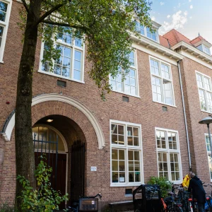 Exterieur Buurthuis Rosa in Utrecht met boogingang, fietsen en boom voor de deur